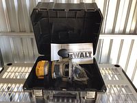 Open black DeWALT hard plastic case showing yellow/grey plunge router and manual inside