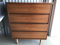Front view of wooden dresser showing four drawers and tapered legs.