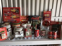 Photo showing entire lot including puzzles, books, glassware, ceramic containers, and collectibles all Coca-Cola themed