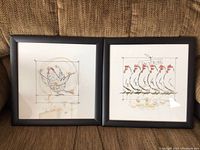 Photo displaying both framed artworks together on a couch, showing the full images of each piece and the frames.