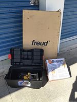 Lot overview showing Freud table box, DeWalt router in plastic case and Dustopper box