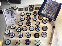 Overall view of table with hockey pucks, cards, photo prints, binder and souvenir stick