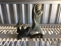 Four Indigenous stone sculptures consisting of mother and child figure, walrus, and two seals arranged on a shelf with industrial background