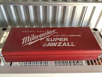 Red metal case closed, showing Milwaukee Super Sawzall branding on top with white text, some wear and scratches on surface.