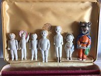 Set of 7 miniature porcelain figurines in a vintage case with satin lining, showing condition and size.