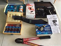 Overview of all items on table including router bit set, soldering tools, drill pump kit, and cutters