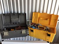 Overall view of two toolboxes: black toolbox open showing tools inside and yellow toolbox open containing assorted tools and parts.