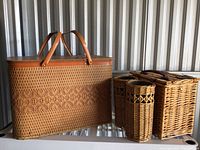 Front and side view of the picnic basket and two wicker carriers, showing woven texture and leather handles.