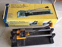 Maestro 13 inch tile cutter in front of its original packaging box showing branding.
