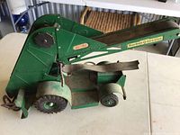Side view of green die-cast Barber Greene toy showing structure, wheels, and fabric belt in used condition with dust and wear