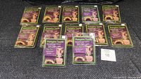 Twelve sets of Stay-Put vampire teeth in sealed packaging displayed together on a black surface.