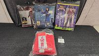 Five children's costumes in packaging displayed flat