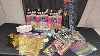 Wide view of the costume accessories lot including gold faux chains, nurse hat, crown, toy trumpet, and Big Baby wigs in packages.