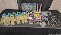 Wide view of costume accessories lot showing necklace packs, bracelets, and jewelry pieces on black surface
