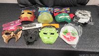 Photo showing 8 assorted plastic and foam costume masks including Iron Man, Ninja Turtle, Frankenstein, and other Halloween themes