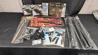 Full view of the cowboy and police costume accessories laid out on a black surface including toy guns, handcuffs, batons, badges, patches, and spurs in packaging.