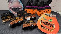 Overall view of Halloween decorations including glittery haunted houses, pumpkin decorations, pumpkin face decoration, and shark mask.