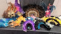 Collection of colorful feathered head dresses and belts arranged on a surface.