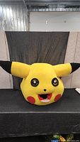 Front view of large Pikachu mascot head with ears spread wide.