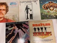 Five vinyl records displayed showing cover artwork from various artists