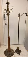 Full view of brass coat rack with wooden fluted base next to brass bridge lamp