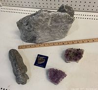 Lot layout showing carved stone buffalo or musk ox, two amethyst clusters, rough rock, and small decorative metal item with ruler for scale