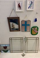 Wide view showing all stained and leaded glass pieces hanging and standing against pegboard