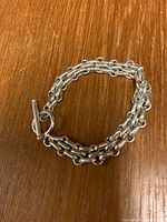 Solid sterling silver heavy bracelet coiled on wooden surface