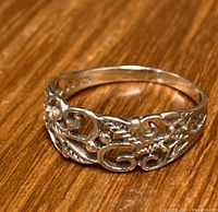 Front view showing detailed filigree design on the sterling silver ring resting on a wooden surface.
