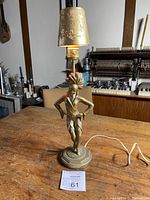 Full view of the standing dancing lady metal lamp with conical gold shade showing wear.