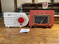 Both radios side by side on wooden surface showing Shelbern white radio with red knobs and Capehart red radio with gold knobs