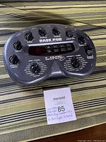 Top view of the Line 6 Bass POD showing control knobs, buttons, display screen, and labeling on fabric background.