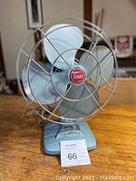 Front view showing the blue metal fan blades behind a circular metal cage and the Torcan logo at center.