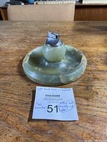 Full view of jade ashtray with lighter placed in the center showing size and condition including a note with item details.