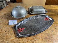 View of the three items: covered bowl, small tray with lid, and large serving tray on wooden table.