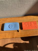 Two leather wallets placed on a wooden surface under sunlight, one blue and one orange