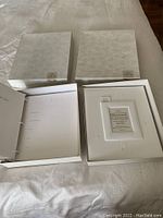 Two new baby photo albums with their boxes, shown open to display inside with personalized photo frame insert.