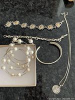Five pieces of costume jewelry including bracelets, bangle, and necklace displayed on a black surface