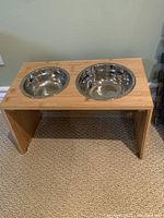 Top view showing the bamboo stand with two circular cutouts holding two stainless steel bowls.