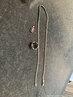 Full view of the three jewelry pieces laid out including necklace, ring, and pink square pendant