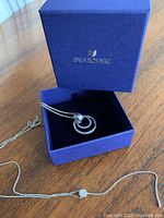 Swarovski pendant necklace in original blue Swarovski box on wooden table.
