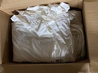 Box of folded white t-shirts showing a large quantity inside a cardboard box.