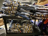 Stacked folded San Diego Padres Majestic MLB t-shirts on shelf, many packed in plastic.
