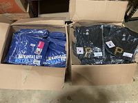 Two open boxes showing stacked and individually packaged Kansas City Royals blue shirts and Pittsburgh Pirates black shirts.