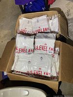 Two open cardboard boxes filled with individually plastic packaged white Cleveland Indians T-shirts printed with red text and logo.