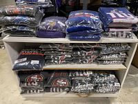Overview of folded hoodies in plastic packaging showing assorted NFL team logos including Broncos, Lions, Vikings, Giants, 49ers, Jaguars