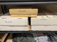 Five storage boxes on a shelf, labeled as baseball and football. Boxes contain trading cards neatly organized inside.