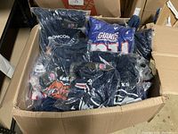 Box full of individually bagged NFL polyester t-shirts showing various team logos including Broncos, Giants, Seahawks.