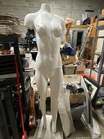 Full front view of the female mannequin showing torso, arms, and legs in warehouse environment.