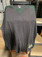 Front view of dark gray and green waffle-knit Milwaukee Bucks men's thermal with logo at front lower hem.